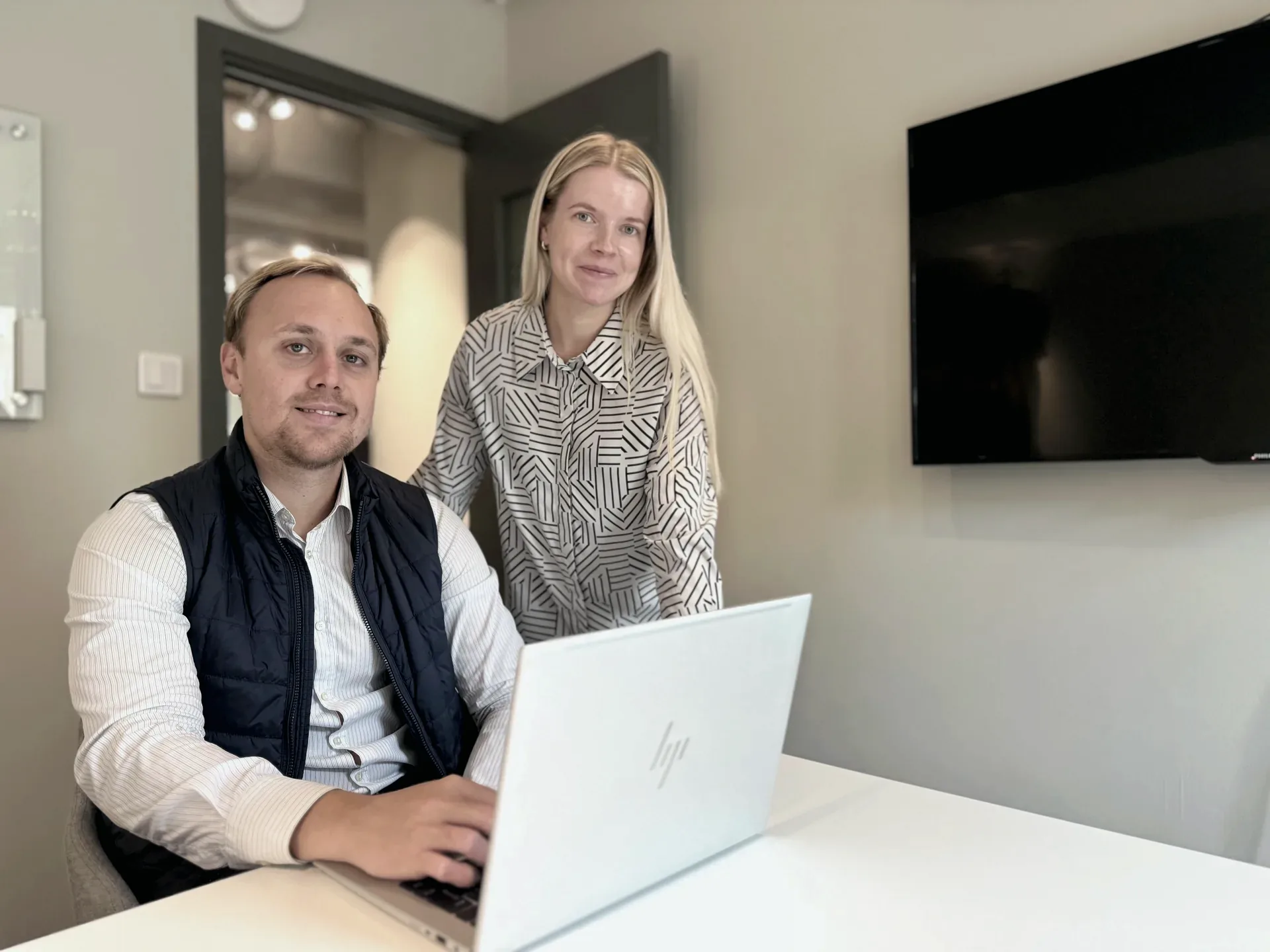 Två kollegor arbetar vid en laptop i ett mötesrum